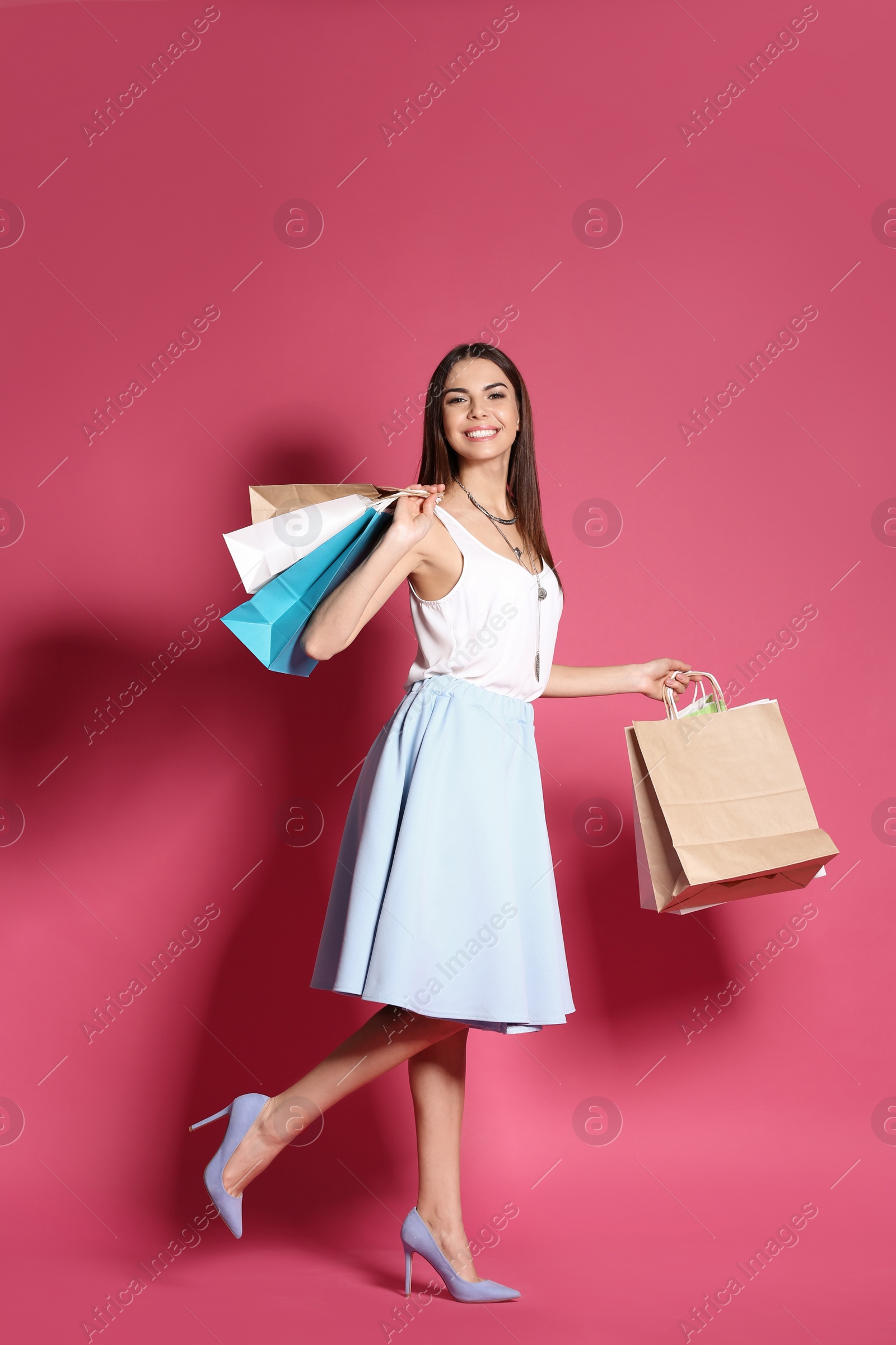 Photo of Young woman with shopping bags on color background