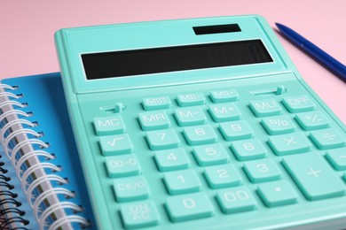 Calculator, notebooks and pen on pink background, closeup