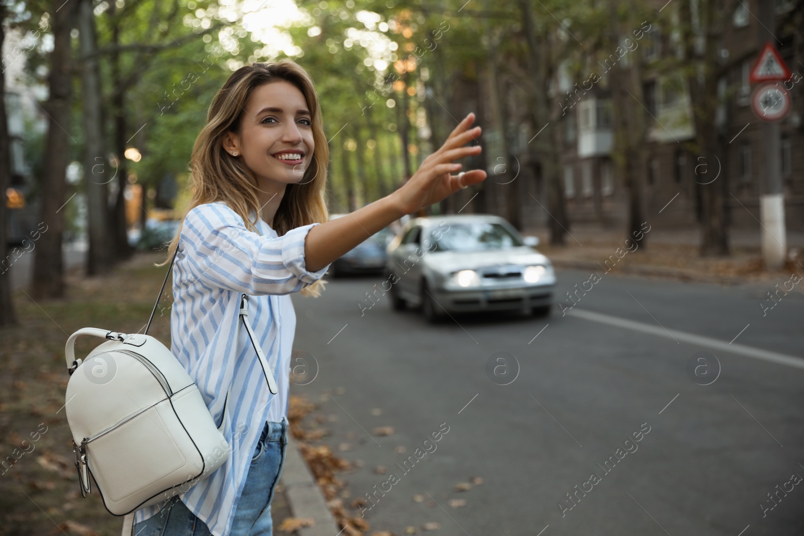 Photo of Young woman catching taxi on city street