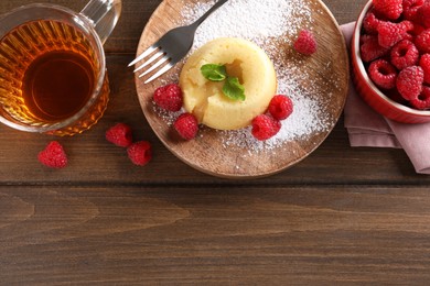 Photo of Tasty vanilla fondant with white chocolate and raspberries served on wooden table, flat lay. Space for text