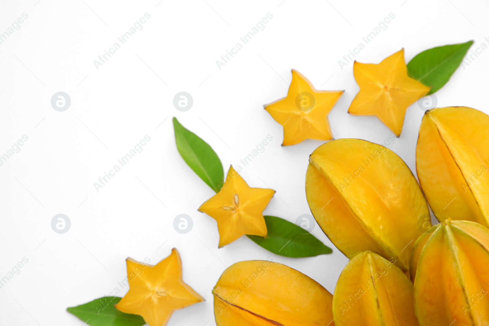 Photo of Delicious cut and whole carambolas, green leaves on white background, top view