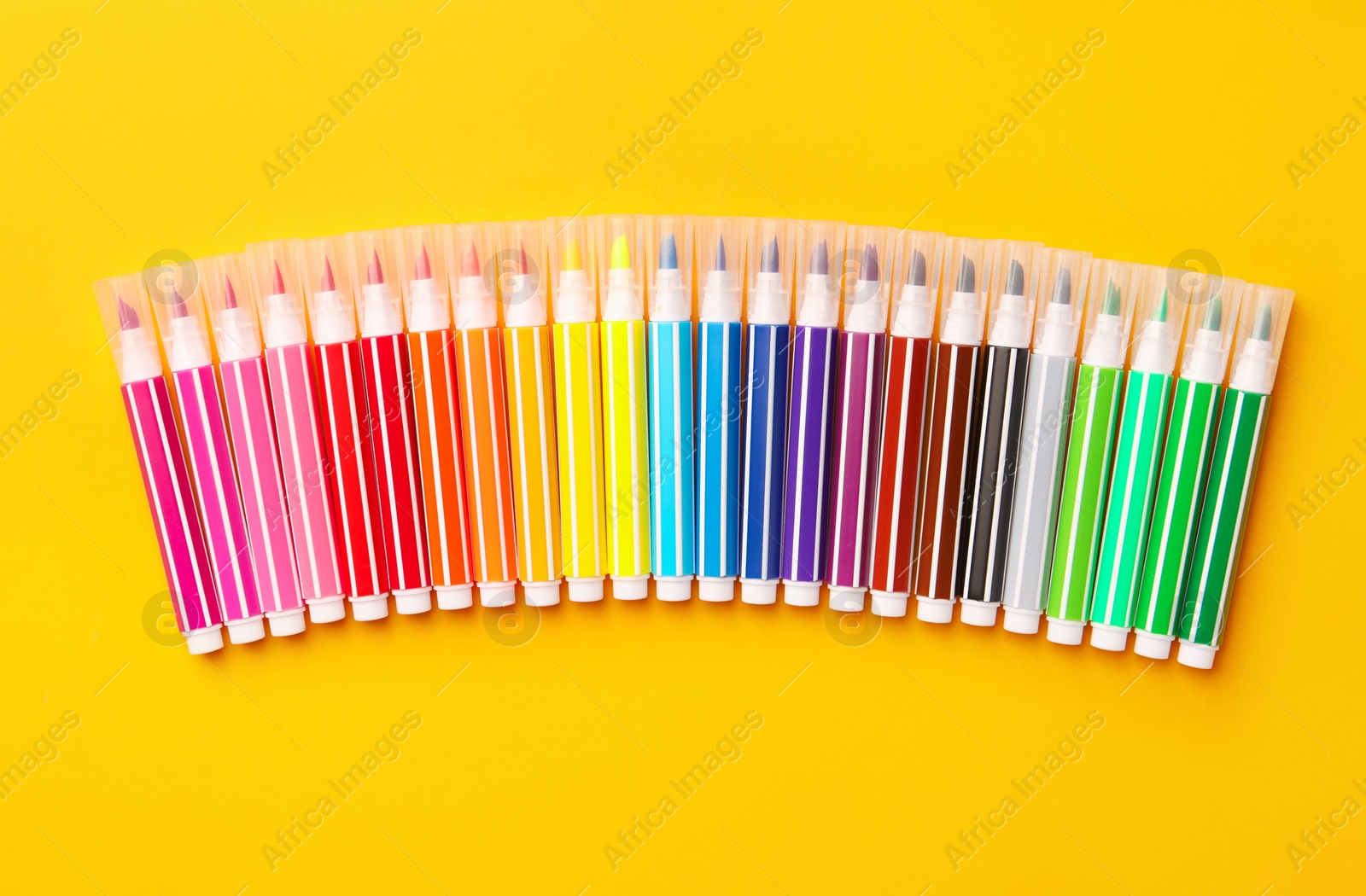 Photo of Many bright markers on yellow background, flat lay