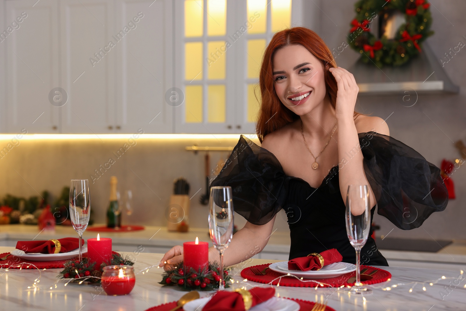 Photo of Beautiful young woman setting table for Christmas celebration in kitchen