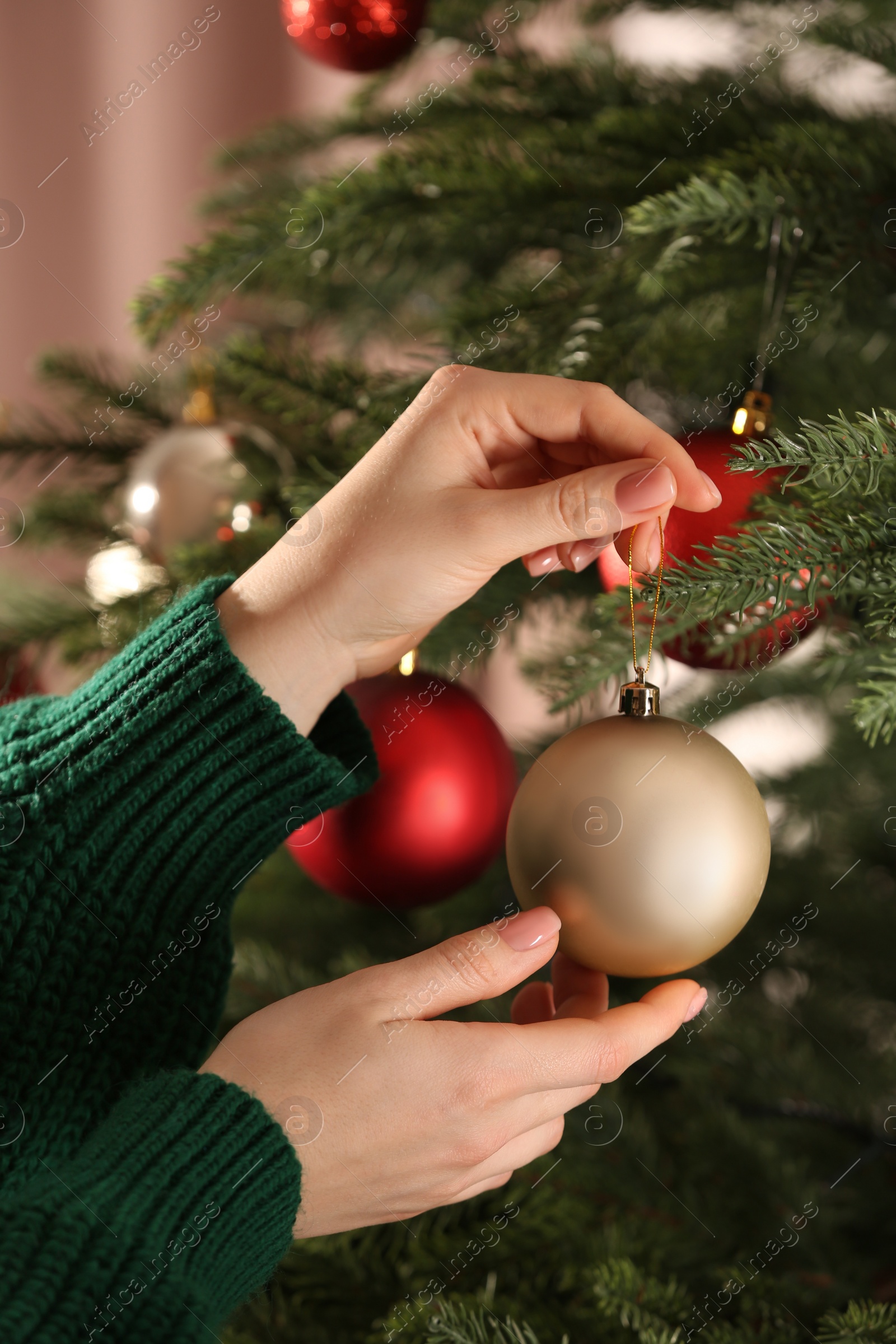 Photo of Woman decorating Christmas tree with beautiful golden bauble, closeup