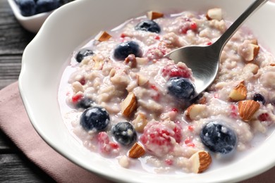 Photo of Tasty oatmeal porridge with toppings on wooden table, closeup