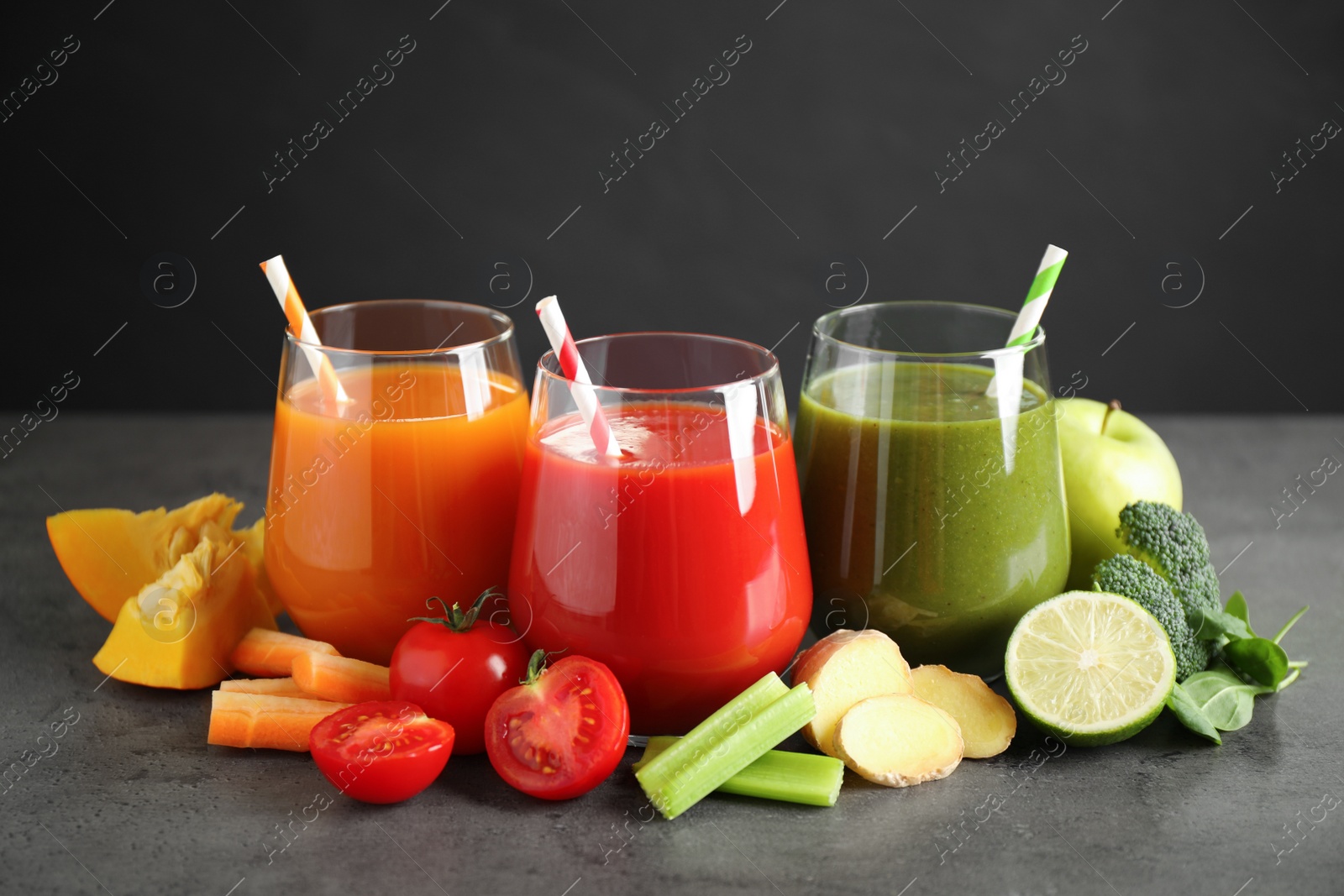 Photo of Different tasty juices and fresh ingredients on grey table