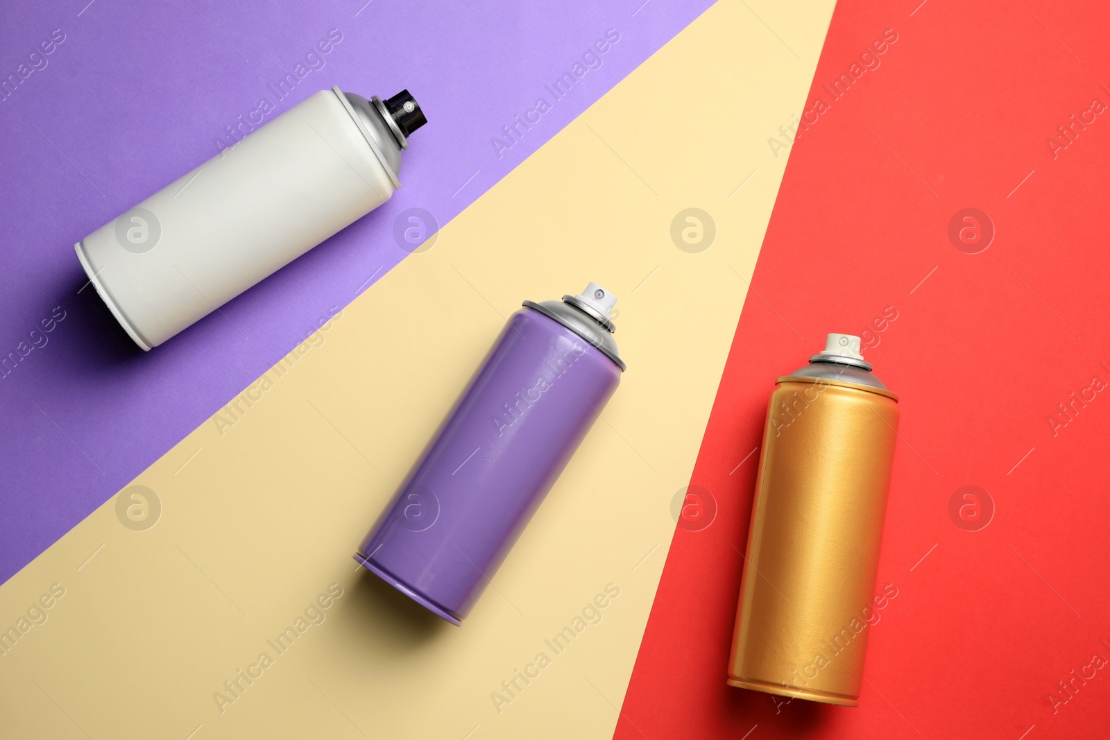 Photo of Cans of different spray paints on color background, flat lay. Graffiti supplies