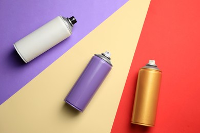 Cans of different spray paints on color background, flat lay. Graffiti supplies