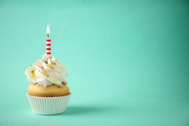 Photo of Delicious birthday cupcake with candle on light green background. Space for text