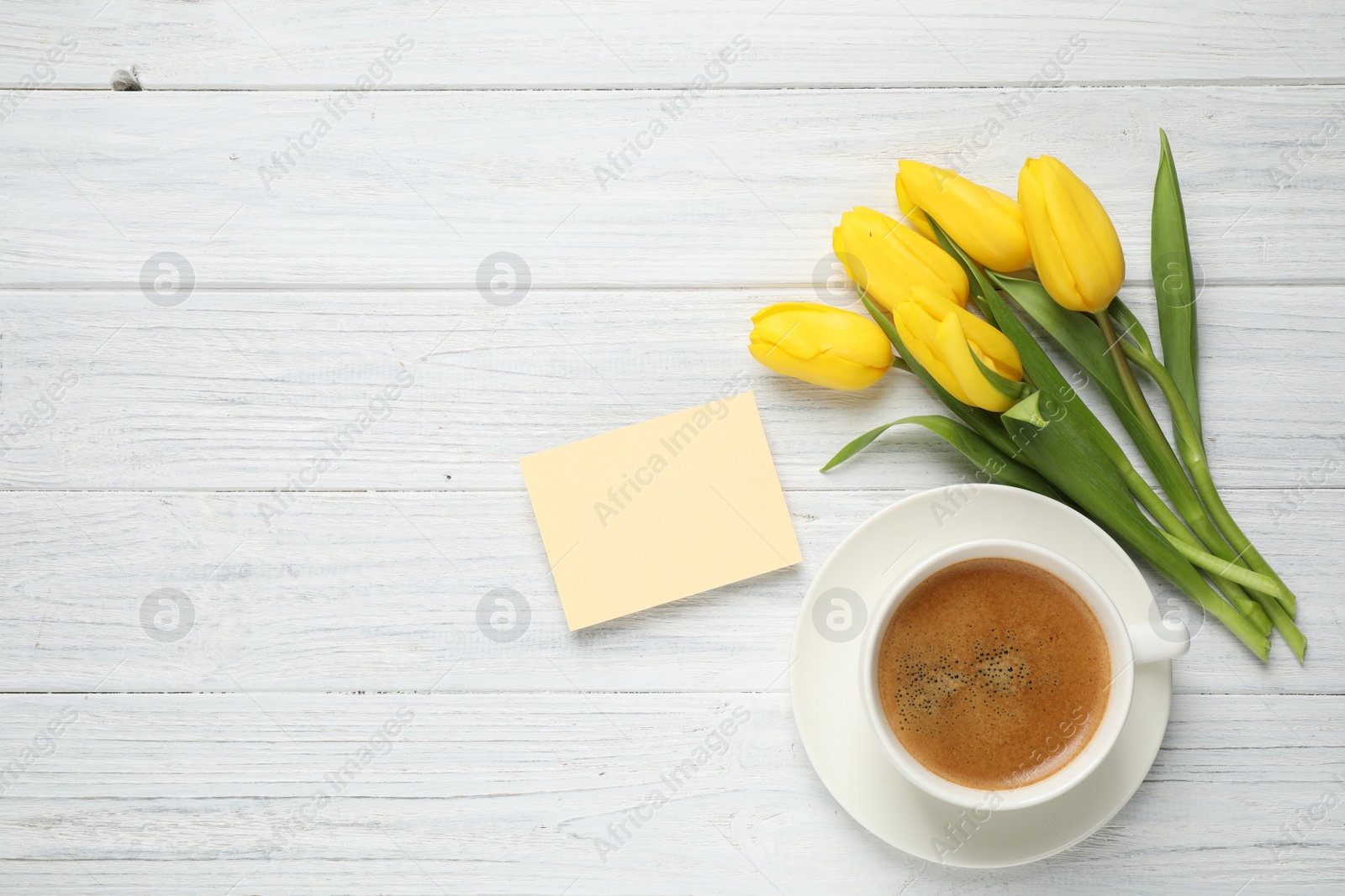 Photo of Yellow tulips, coffee and blank card on white wooden table, flat lay with space for text. Good morning