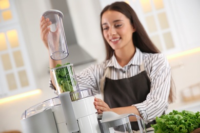 Photo of Young woman making tasty fresh juice in kitchen, focus on hands
