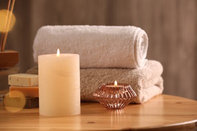 Photo of Spa composition. Burning candles, towels and soap on wooden table