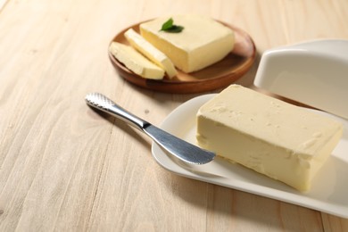 Tasty butter and knife on wooden table