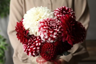 Photo of Woman with bouquet of beautiful dahlia flowers indoors, closeup