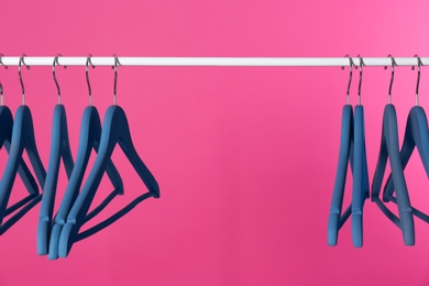 Metal rack with clothes hangers on color background, space for text