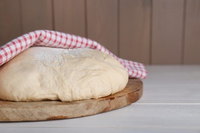 Photo of Fresh yeast dough with flour on white wooden table. Space for text