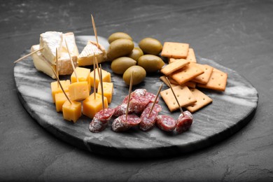 Photo of Toothpick appetizers. Pieces of sausage, cheese and crackers on black table