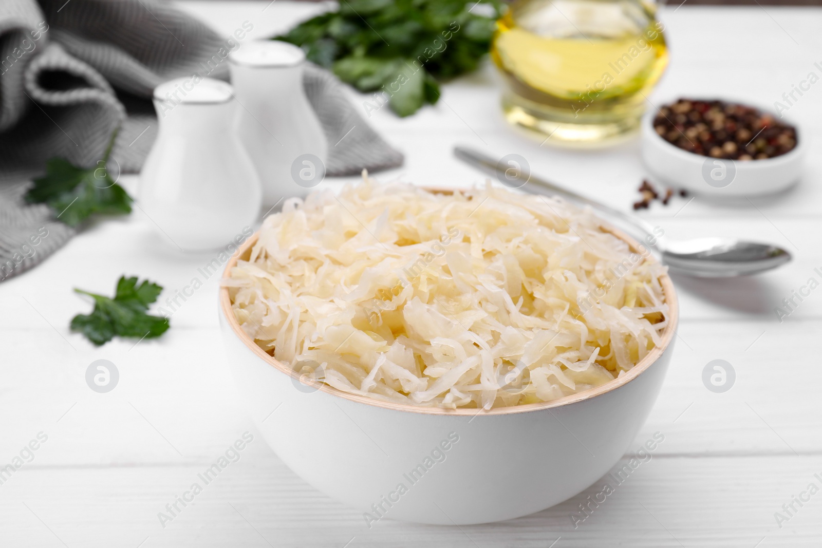 Photo of Bowl of tasty sauerkraut on white wooden table