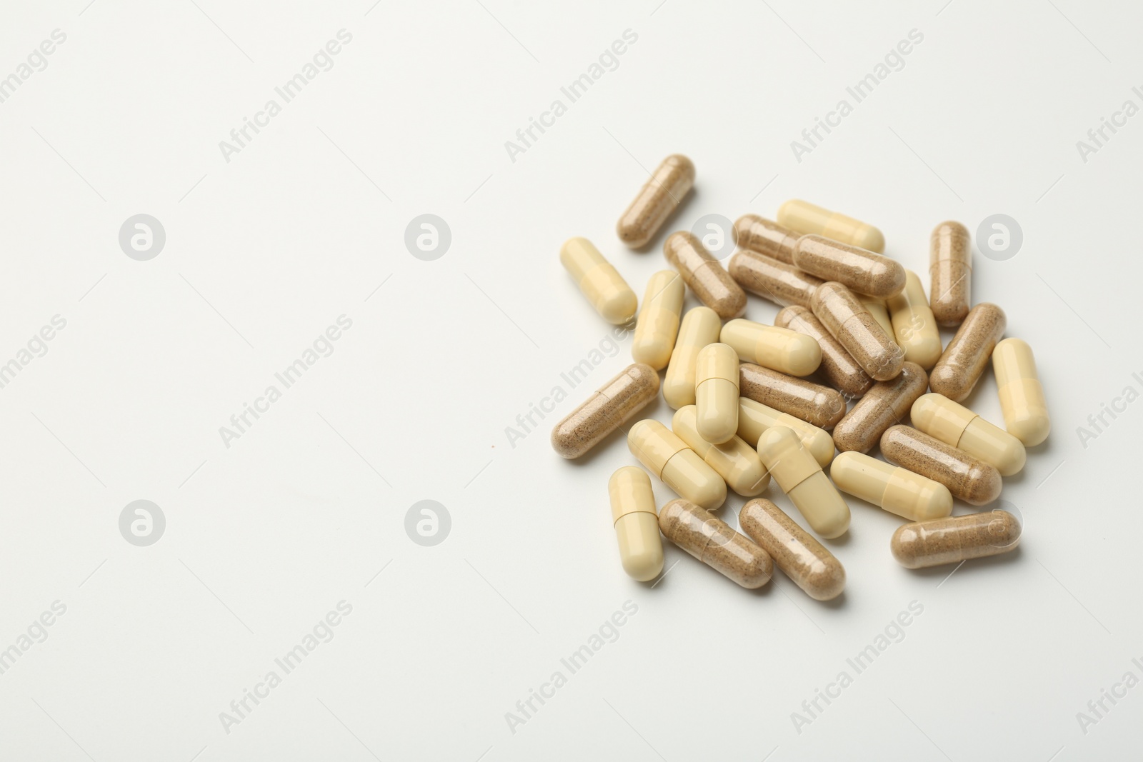 Photo of Different vitamin capsules on white background. Space for text