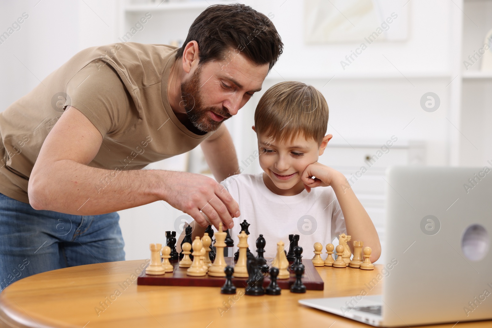 Photo of Father teaching his son to play chess following online lesson at home