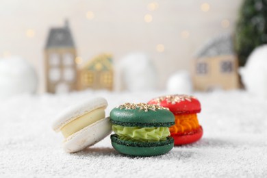 Different decorated Christmas macarons on table with artificial snow