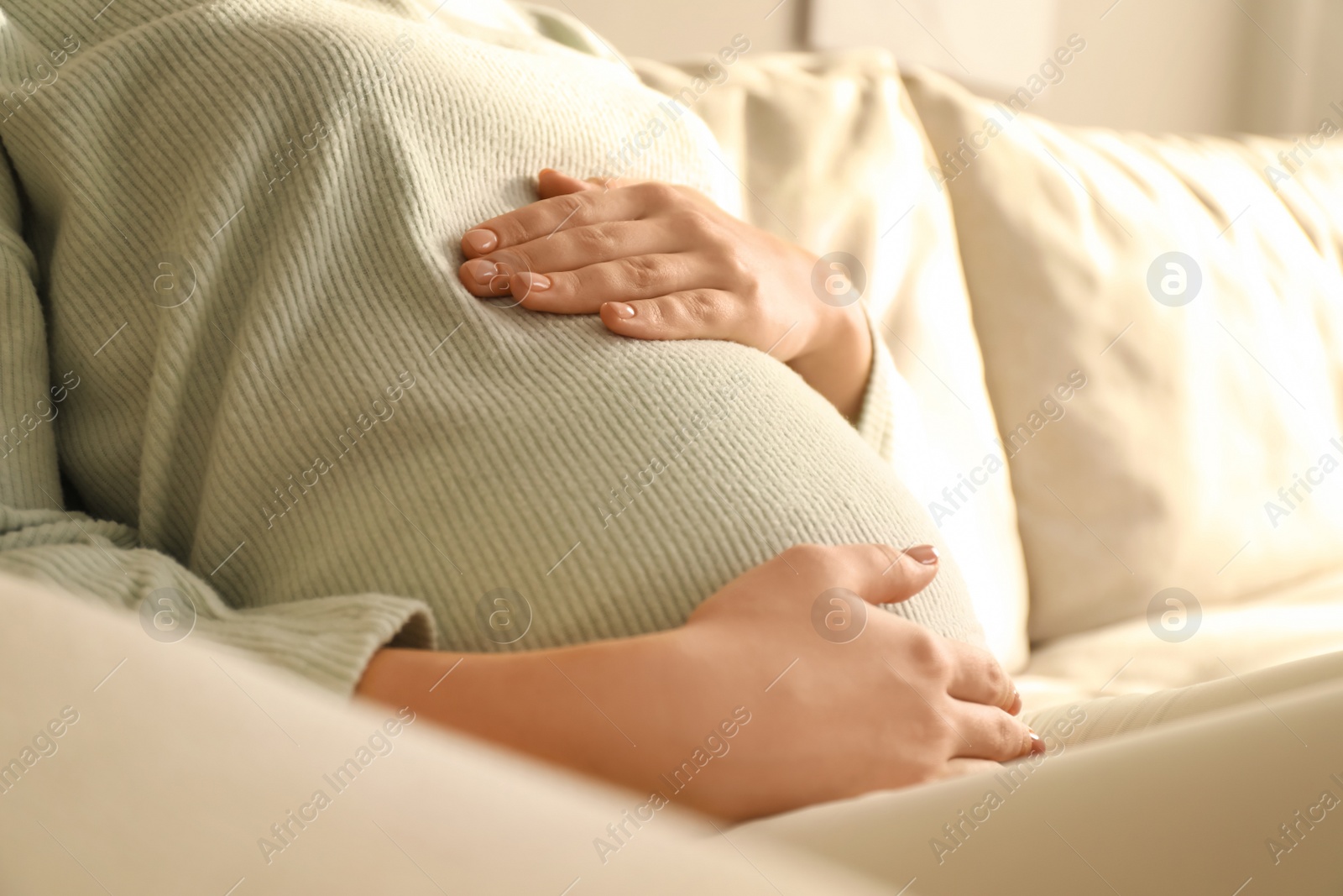 Photo of Pregnant young woman touching belly at home, closeup