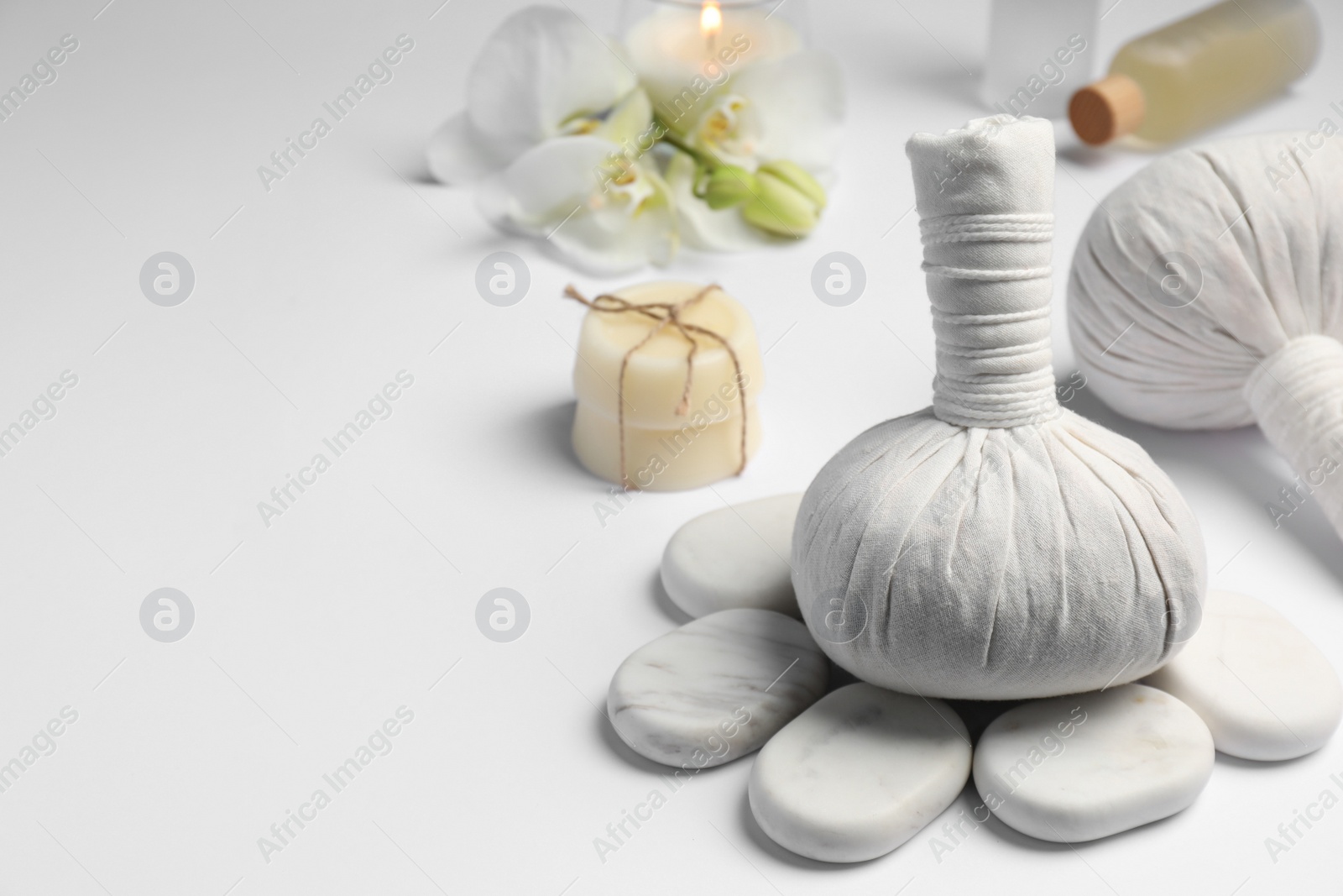 Photo of Herbal massage bags and other spa products on white table, space for text