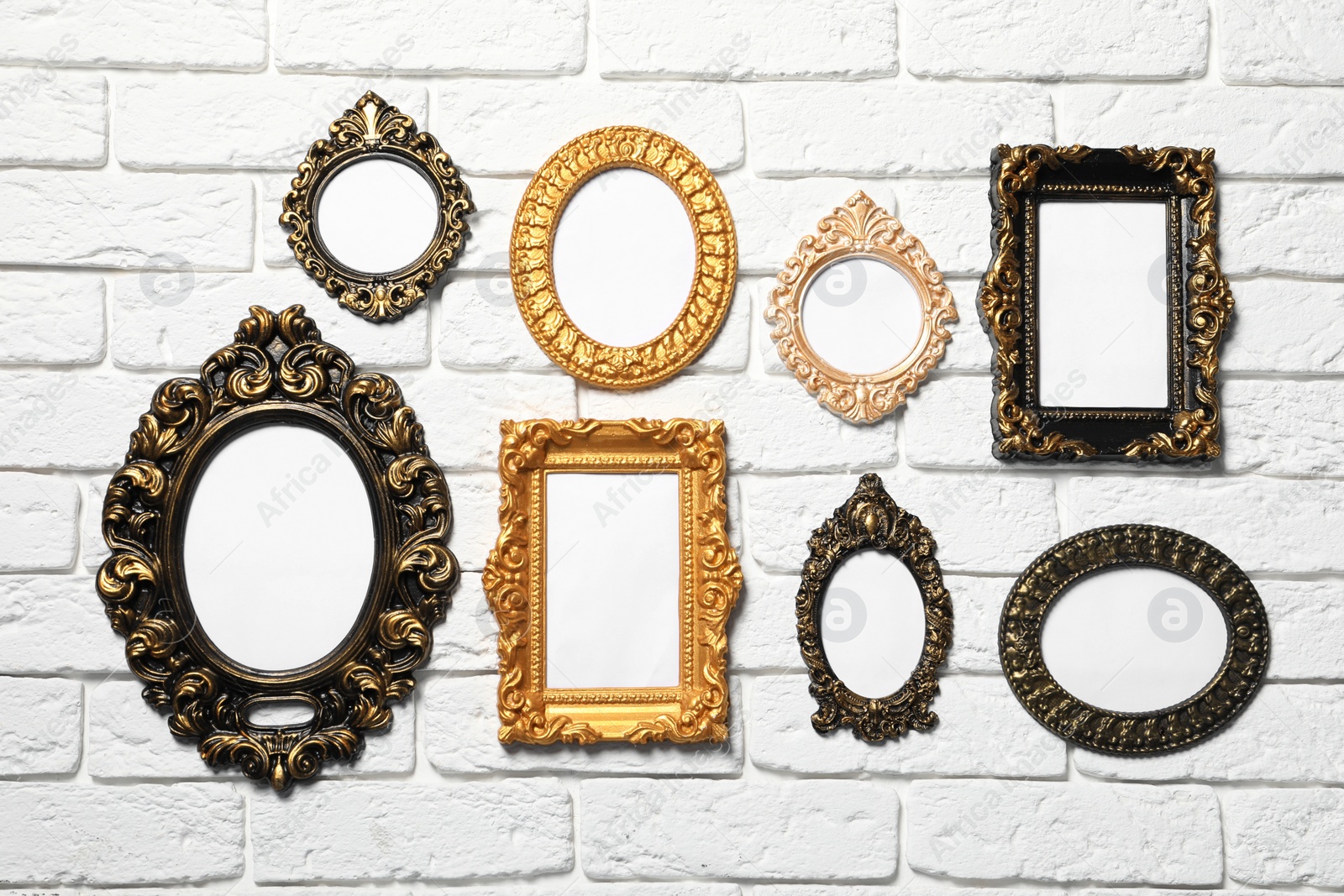 Photo of Blank vintage frames hanging on white brick wall. Mockup for design