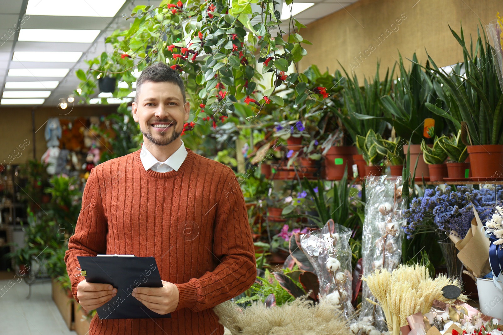 Photo of Male business owner with clipboard in his flower shop