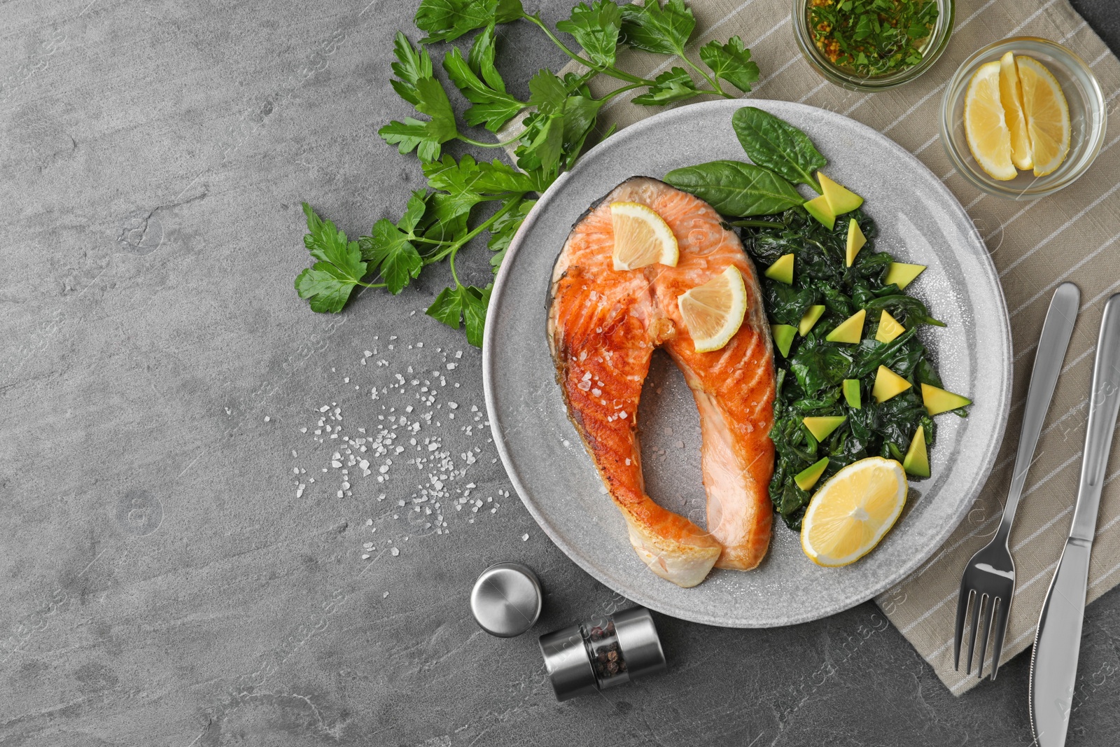 Photo of Tasty salmon with spinach served on grey table, flat lay