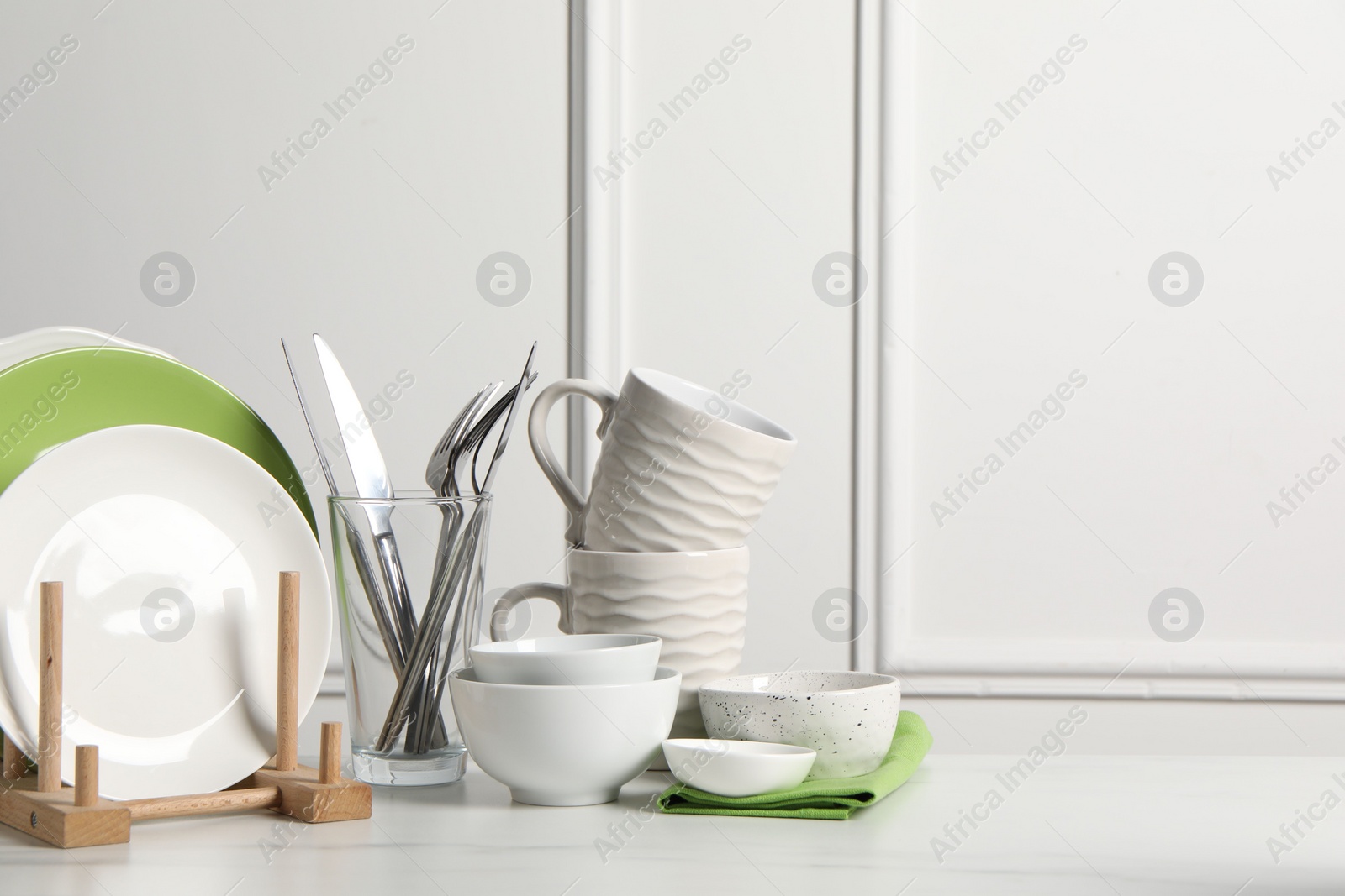 Photo of Beautiful ceramic dishware, cups and cutlery on white marble table, space for text