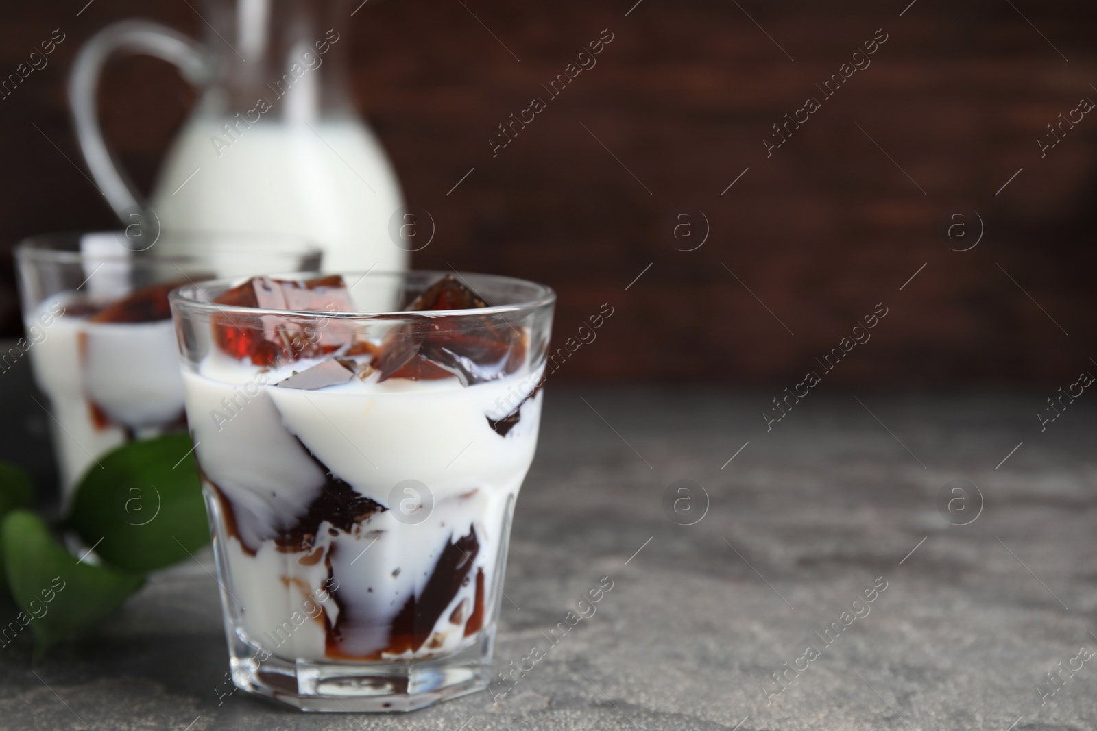 Photo of Glasses of milk with delicious grass jelly on grey table, closeup. Space for text