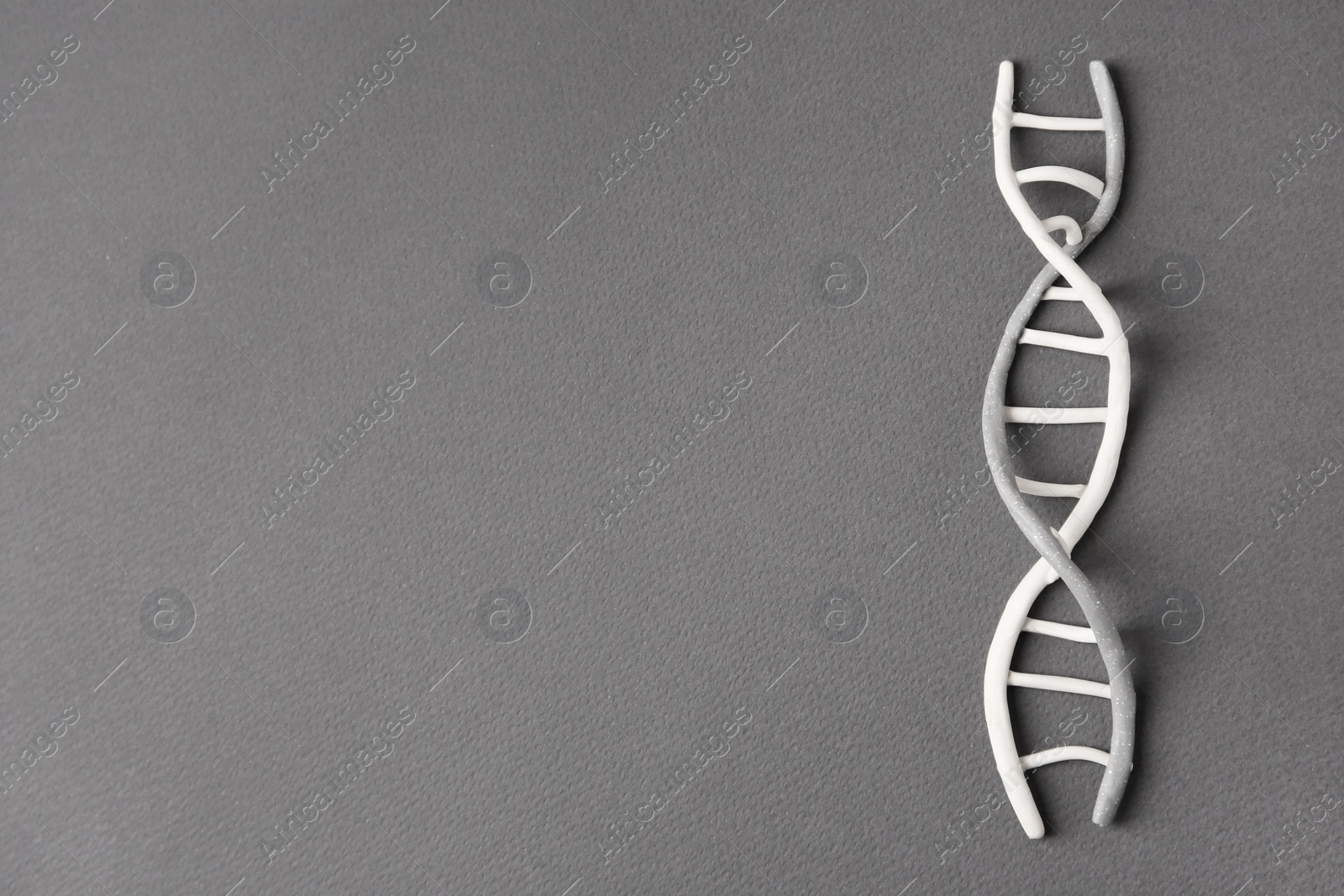 Photo of DNA molecule model made of grey plasticine on black background, top view. Space for text