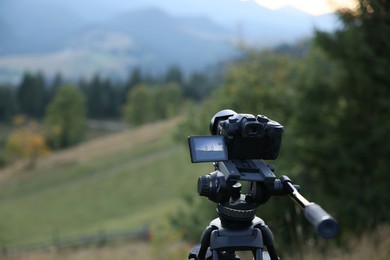 Photo of Taking photo of beautiful mountain landscape with camera mounted on tripod outdoors, space for text