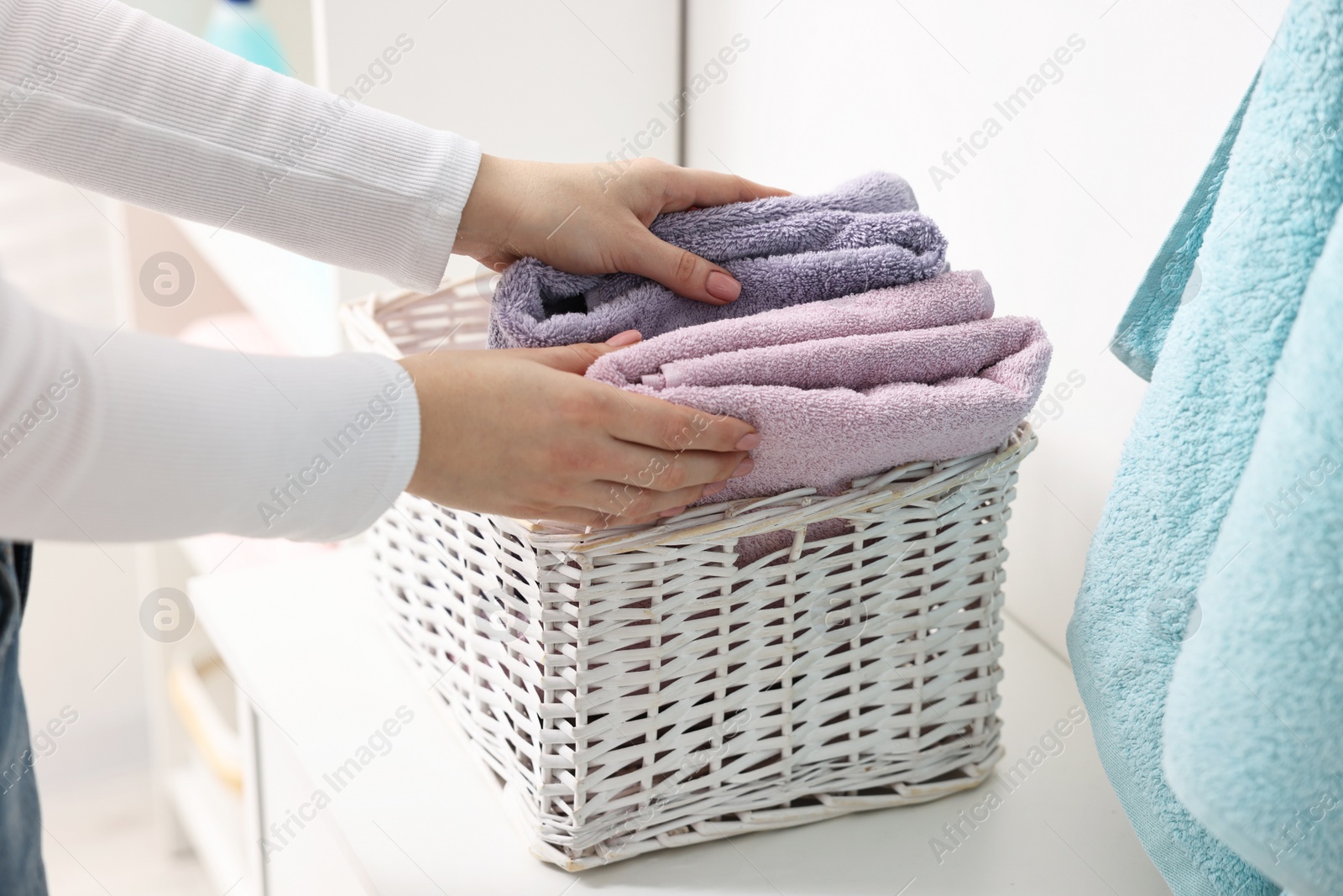 Photo of Woman with laundry basket of clean towels indoors, closeup