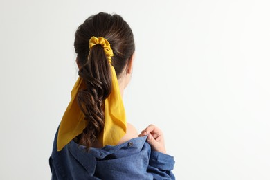 Photo of Young woman with stylish yellow bandana on light background, back view. Space for text