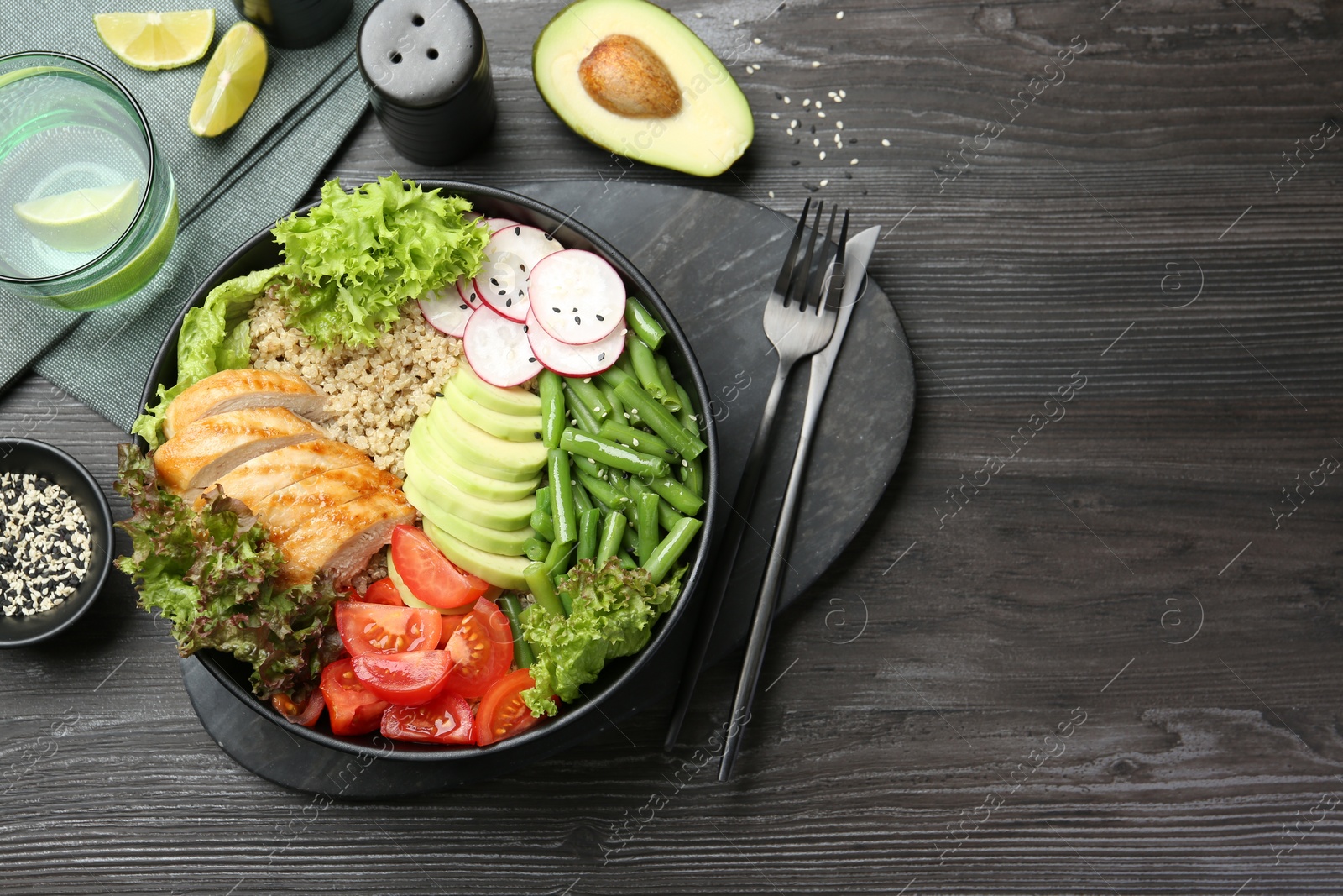 Photo of Healthy meal. Tasty products in bowl and cutlery on black wooden table, flat lay. Space for text