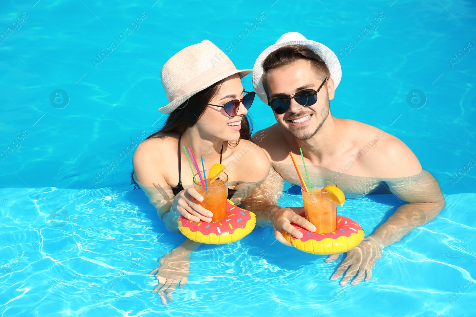 Photo of Young couple with refreshing cocktails in swimming pool on sunny day