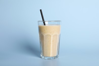 Photo of Glass of tasty smoothie with straw on light blue background