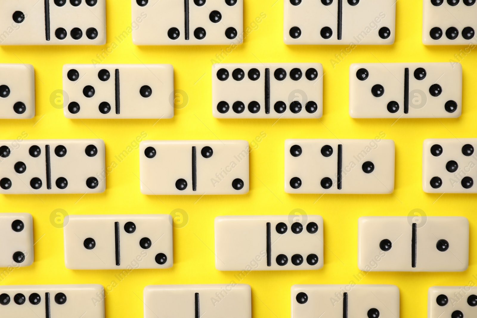 Photo of Classic domino tiles on yellow background, flat lay