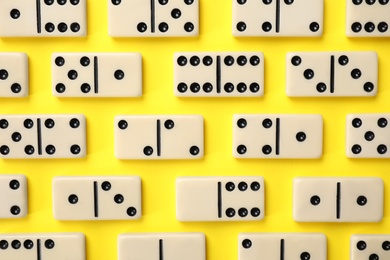 Photo of Classic domino tiles on yellow background, flat lay