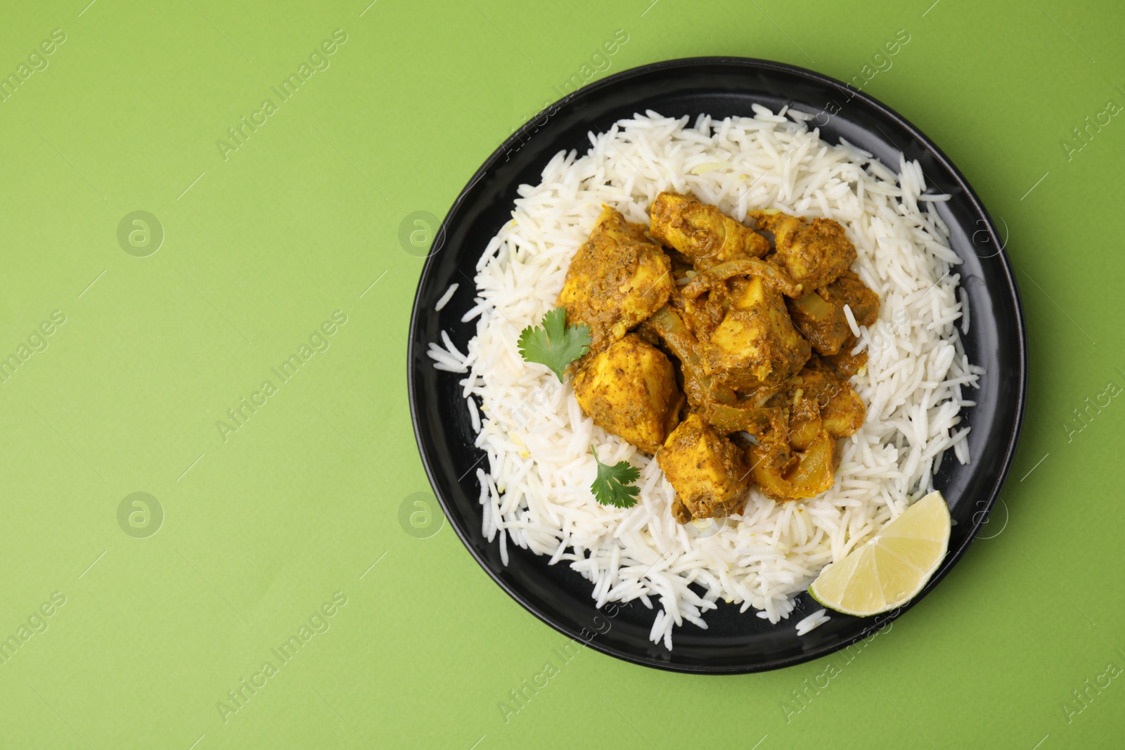 Photo of Delicious chicken curry with rice on green background, top view. Space for text