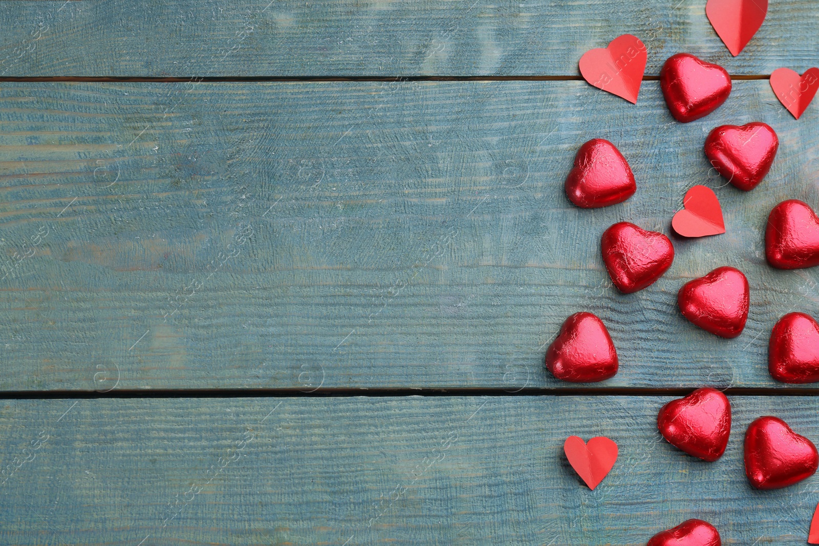 Photo of Heart shaped chocolate candies on blue wooden table, flat lay with space for text. Valentine's day celebration