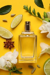 Photo of Flat lay composition with bottle of perfume and fresh citrus fruits on yellow background