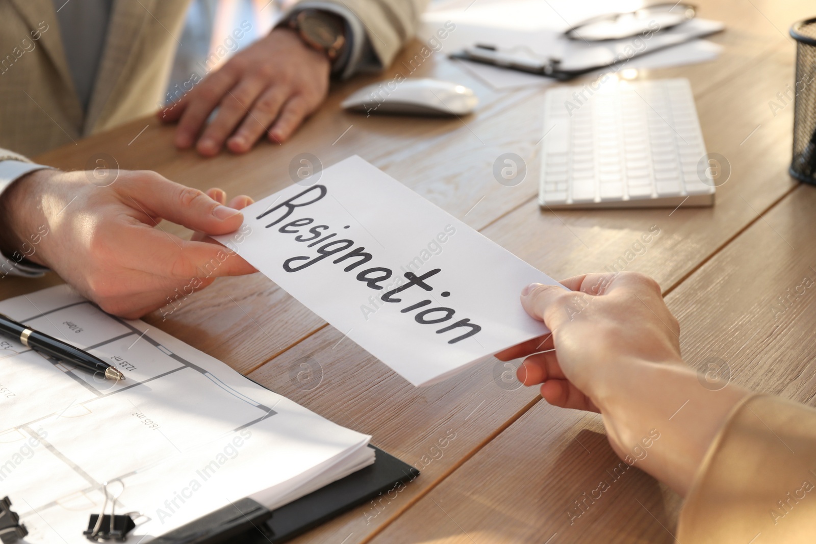 Photo of Employee giving resignation letter to boss in office, closeup