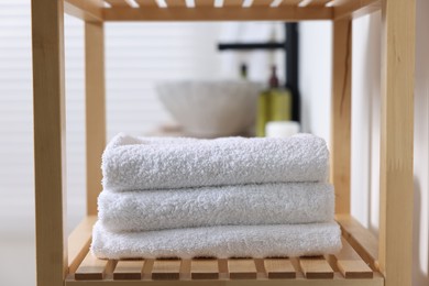 Photo of Stacked bath towel on wooden shelf indoors