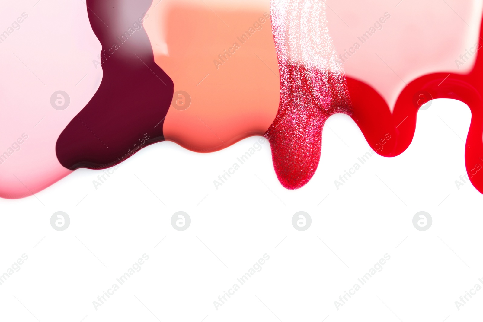 Photo of Colorful nail polishes spilled on white background