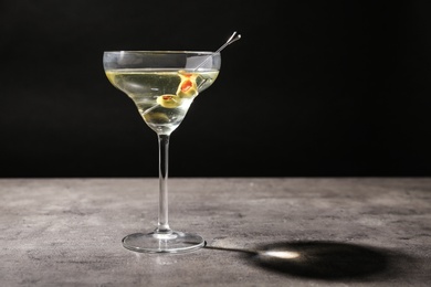 Photo of Glass of Classic Dry Martini with olives on grey table against black background. Space for text