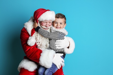 Photo of Little boy hugging authentic Santa Claus on color background