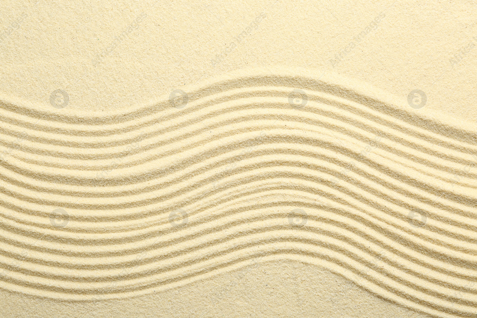 Photo of Zen rock garden. Wave pattern on beige sand, top view